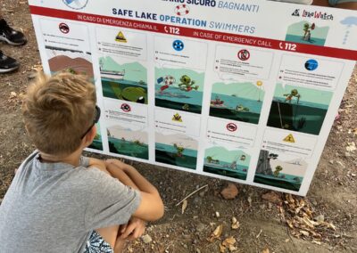 Un bambino legge le norme di sicurezza per i bagnanti a Mandello del Lario